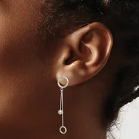 Silver drop earring with circular top and elongated stem ending in a small ball, worn on the earlobe of a person with medium brown skin tone.