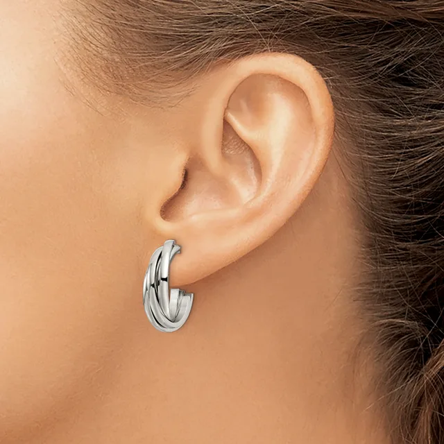 A silver hoop earring with a twisted or braided texture worn on a person's earlobe.