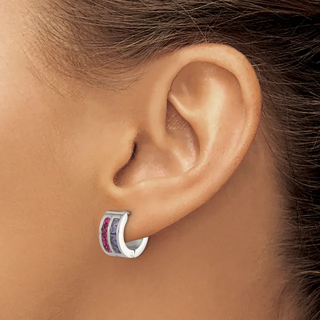 A person wearing a silver hoop earring with purple and pink stone inlays on their earlobe.