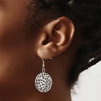 A woman wearing a silver filigree circular disc earring with an open lattice pattern hanging from a hook fastener on her earlobe.