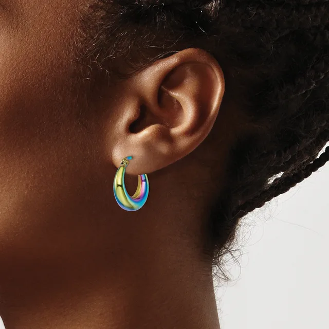 Close-up side view of a person's ear wearing a small stud earring and a colorful rainbow hoop earring with yellow, green, blue, and pink tones.