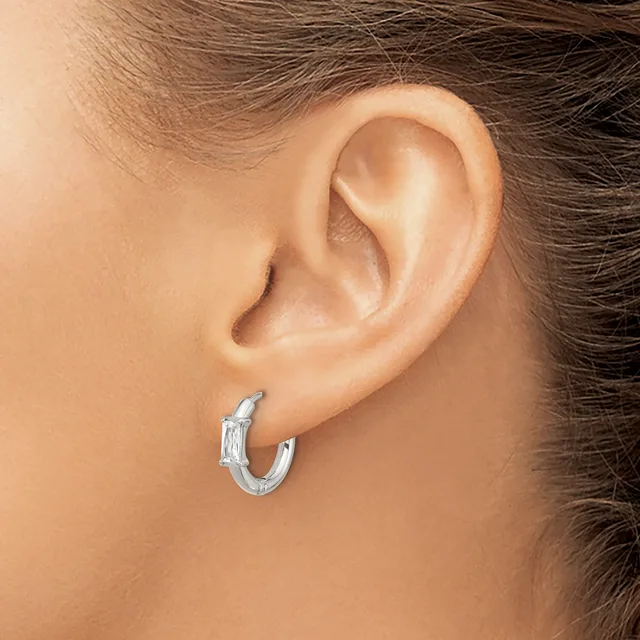 A person wearing a pair of textured silver hoop earrings with a hammered finish, shown from the side view of their ear.