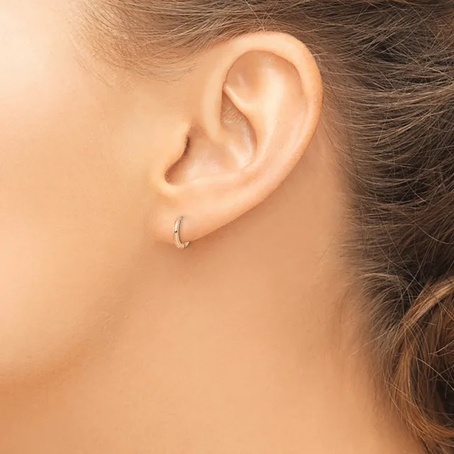 A person's ear wearing a small silver hoop earring, shown in profile against a neutral background.