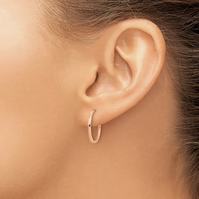 A person wearing a small polished silver hoop earring in their earlobe, shown in profile view.