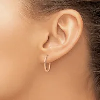 A person wearing a small polished silver hoop earring in their earlobe, shown in profile view.