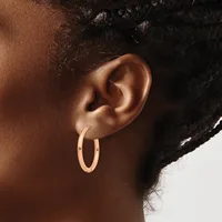 A person wearing rose gold hoop earrings is shown in profile from the shoulders up, with dark hair pulled back.