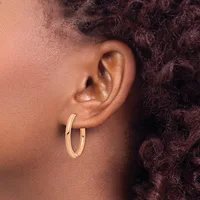 A person wearing gold hoop earrings is shown in profile, displaying their ear and dark curly hair against their skin.