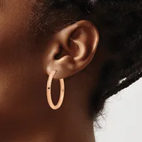 A person wearing rose gold hoop earrings is shown in profile, displaying the earrings against their ear and neck.