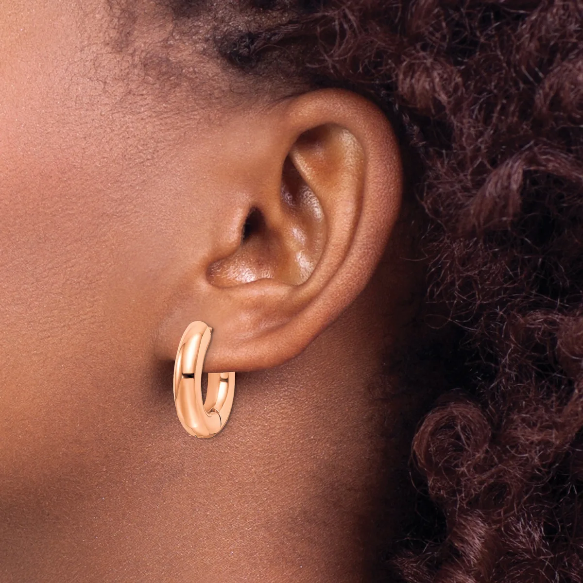 A person wearing a rose gold chunky oval hoop earring visible on their earlobe, shown in profile against their neck and shoulder.