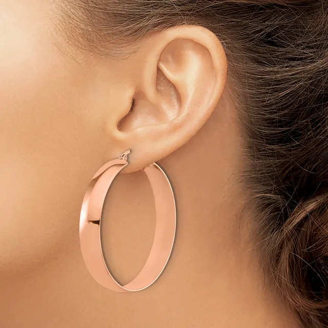 A person wearing a large rose gold hoop earring, shown from the side view of their ear and neck.