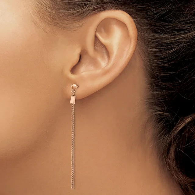 A person wearing a long silver chain earring with a small rectangular connector at the top, shown from the side view of their ear and neck.