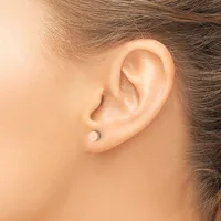 A person wearing a small round stud earring in their earlobe, shown in profile view with brown hair pulled back.