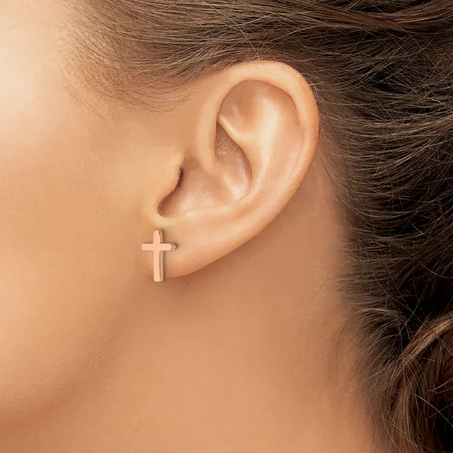 A person wearing a small cross-shaped stud earring in their earlobe, shown in profile view.