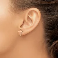 A person wearing a small cross-shaped stud earring in their earlobe, shown in profile view.
