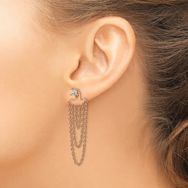 A woman wearing a silver chain earring with a small square gemstone stud at the top, displaying multiple draped chains hanging from the stud.