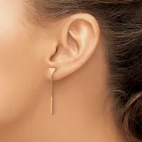 A person wearing a delicate chain threader earring with a thin metal bar, shown from the side profile of their ear.