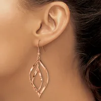 A person wearing a rose gold teardrop-shaped dangle earring with layered leaf-like cutout details, shown from the side view against their ear.