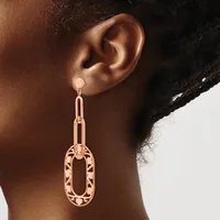 A person wearing a rose gold elongated oval drop earring with geometric cutout patterns, shown from the side against a neutral background.