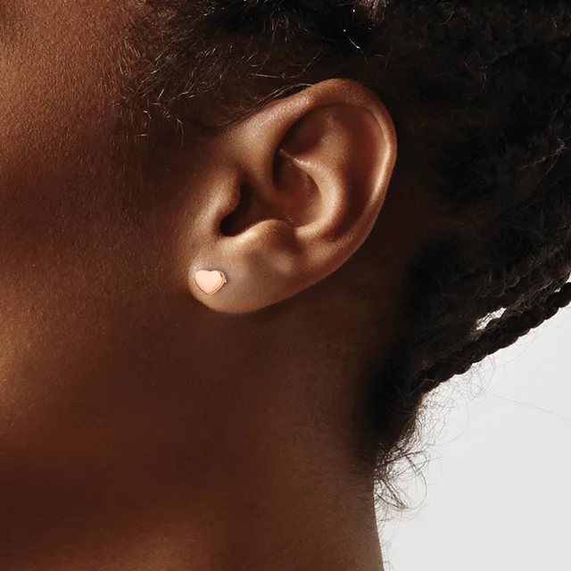 A person wearing a small heart-shaped stud earring in their earlobe, shown in profile against a neutral background.