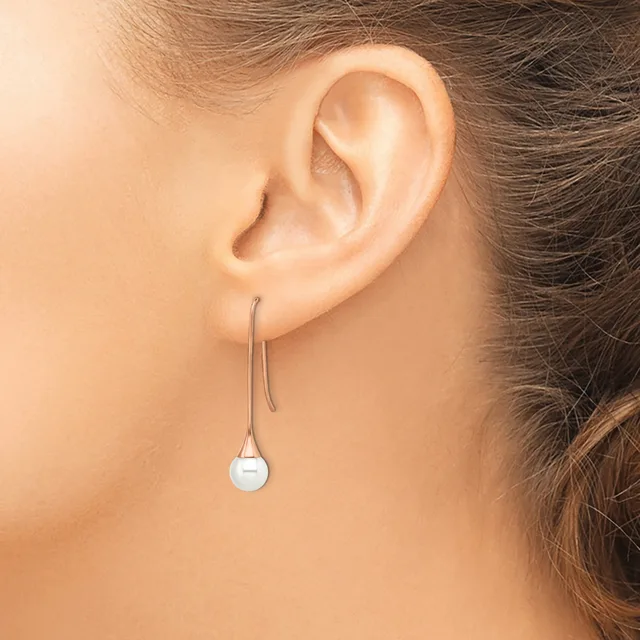 A person wearing a long silver-toned threader earring with a small pale blue spherical stone or bead hanging from the end.