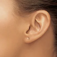 A person's ear with a small silver stud earring in the lobe, shown in profile against a neutral background.