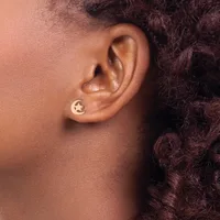 A person with dark curly hair wearing a small silver star-shaped stud earring in their earlobe, shown in profile.