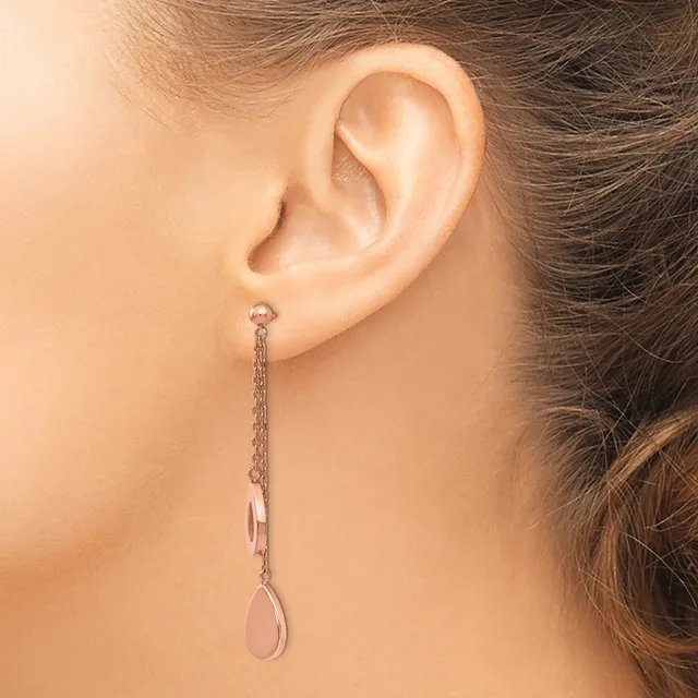 A woman wearing a long rose gold chain dangle earring with a teardrop-shaped stone at the end, shown from the side view of her ear and neck.