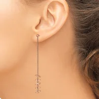 A person wearing a long silver chain earring with small spiral or coil-shaped pendants hanging from the earlobe.
