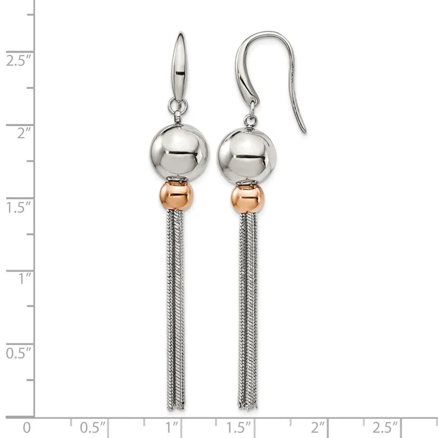 A pair of silver and rose gold dangle earrings with polished spheres and tassel chains, displayed on a measurement scale.