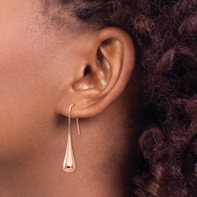 A person wearing a silver teardrop-shaped dangle earring visible against their ear and neck, shown in profile.