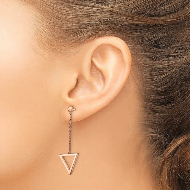 A woman wearing a long dangling earring with a triangular pendant hangs from a thin chain attached to a small stud post.