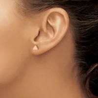 Close-up side view of a person's ear wearing a small triangular stud earring in the lobe.