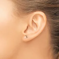 A small triangular stud earring in a polished metallic finish worn in the earlobe of a person shown in profile.