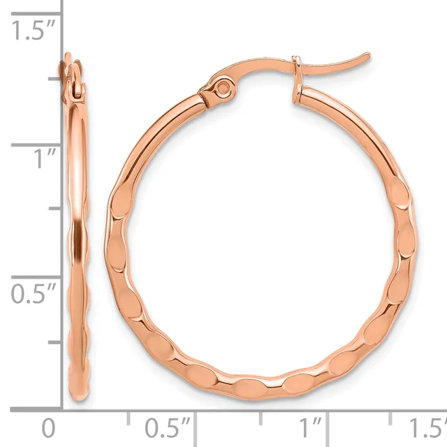 Rose gold hoop earrings with a textured surface and hinged closures, shown against a measurement scale indicating they are approximately 1.5 inches long.