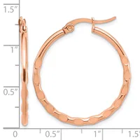 Rose gold hoop earrings with a textured surface and hinged closures, shown against a measurement scale indicating they are approximately 1.5 inches long.