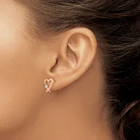 A person wearing a heart-shaped earring with a small diamond accent in their earlobe, shown in profile against their ear and neck.
