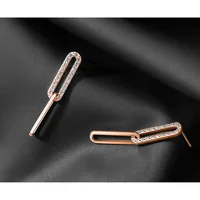 Two rose gold earrings with elongated oval shapes decorated with small crystals or rhinestones along the top edges, displayed on a dark gray surface.
