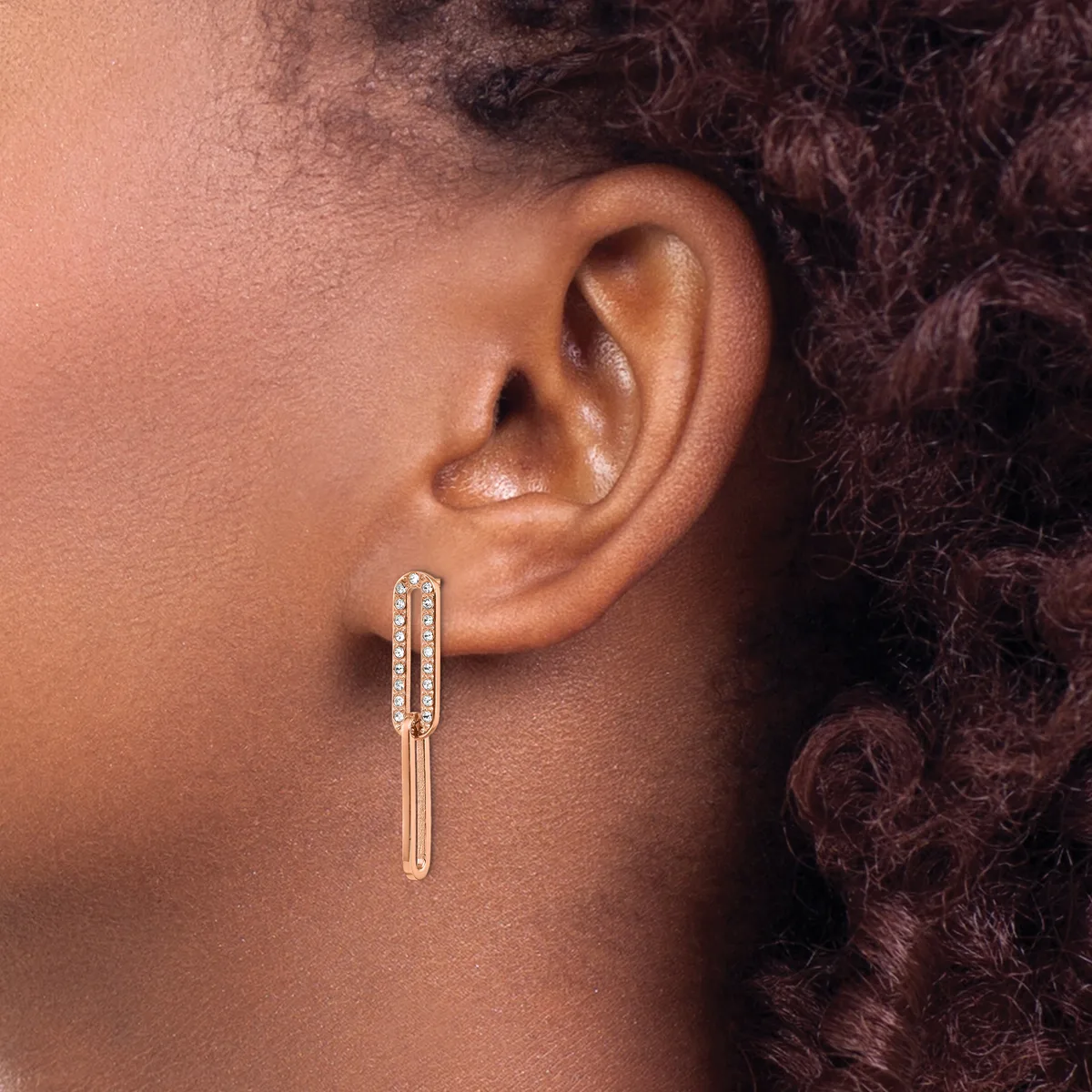 A person wearing elongated rectangular drop earrings with a diamond-paved top section and smooth polished bar extending downward, shown from the side profile.