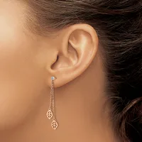 A person wearing long silver chain earrings with small leaf-shaped pendants hangs from pierced earlobes.