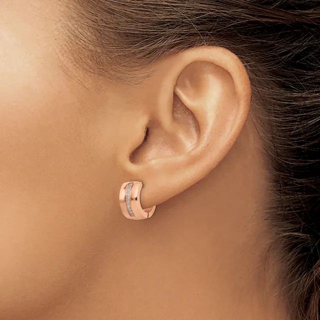 A person wearing a rose gold hoop earring with a diagonal diamond accent, shown from the side profile view of their ear and neck.