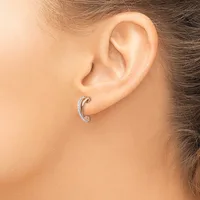 A woman wearing a curved silver hoop earring with diamond accents on her earlobe.
