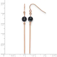 Pair of rose gold-toned earrings with black spherical stones suspended above long thin bars, shown on a measurement scale.