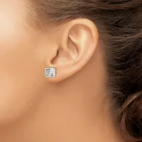 A person wearing a square stud earring with a clear stone set in a silver-toned metal setting, shown on their earlobe.