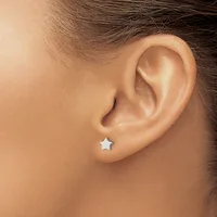 A small silver star stud earring in a pierced earlobe, shown from a side profile view.