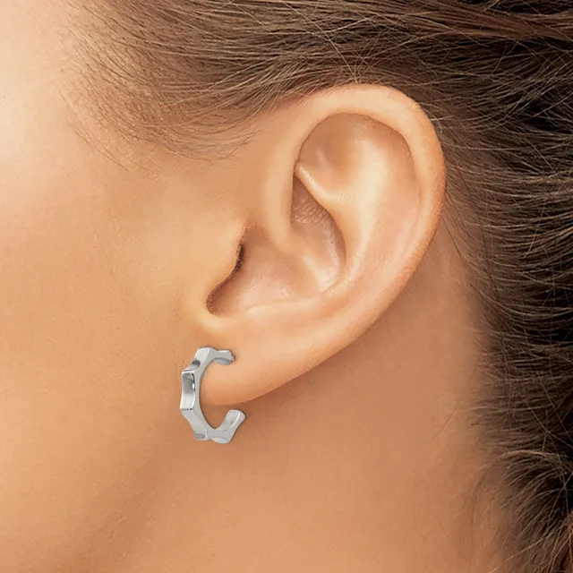 A silver-toned chunky C-shaped hoop earring worn on a person's earlobe, shown in profile view.