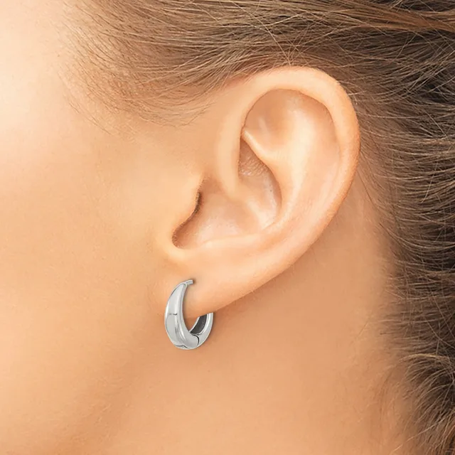 A silver chunky curved hoop earring worn on the earlobe of a person shown from the side, with brown hair pulled back.