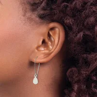 A person wearing silver hook earrings with small white teardrop pendants, shown from the side profile against their ear.