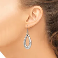 A woman wearing a silver teardrop-shaped dangle earring with a polished finish, shown from the side view against her ear.