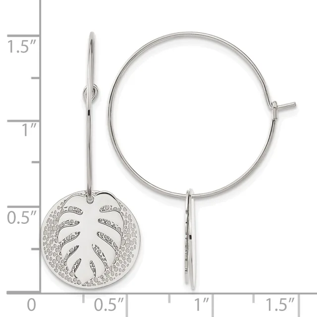 Silver hoop earrings with a circular leaf-motif charm pendant hanging from one ear wire, shown against a measurement scale.