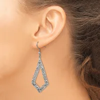 A woman wearing a silver-toned teardrop-shaped dangle earring with textured filigree detailing, shown from the side against her ear.